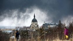 People walk by a church in Lviv as smoke rises after an airstrike 