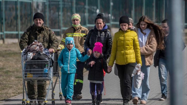 A Polish serviceman helps Ukrainian refugees to cross the Ukrainian border with Poland