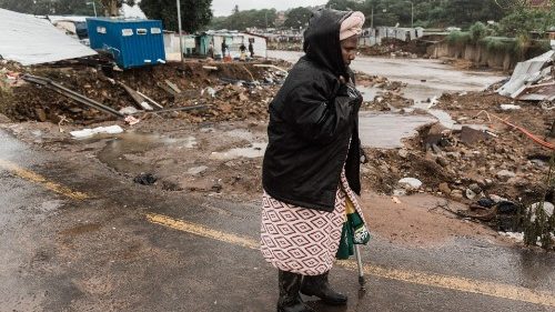 A woman in a drenched raincoat walks past the Quarry road informal settlement outside Durban. 