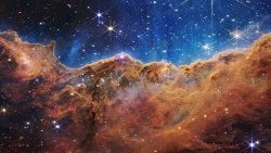 An image from the James Webb Space Telescope shows a landscape of mountains and valleys which is the edge of a nearby, young star-forming region called NGC 3324 in the Carina Nebula