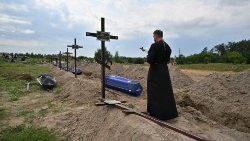 An Orthodox priest serves at the graves of unidentified civilians during a funeral in the city of Bucha, Ukraine