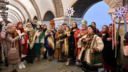 Residentes locais, vestidos com trajes tradicionais, cantam canções de natal dentro de uma estação de metrô em Kyiv em 25 de dezembro de 2022, em meio à invasão russa da Ucrânia. (Foto de Sergei CHUZAVKOV/AFP)