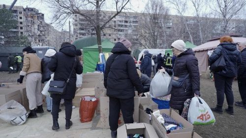 Ucraini portano aiuti sullo sfondo del palazzo bombardato a Dnipro