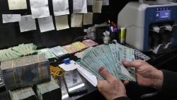 एक आदमी बेरूत में एक मुद्रा विनिमय कार्यालय में लेबनानी पाउंड को पकड़े हुए