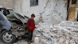 A boy looks at a damaged house following a reported bombing by government forces