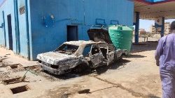 A man walks towards a charred car in a loots petrol station in southern Khartoum, 6 May