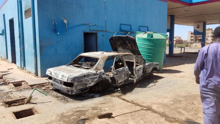 A man walks towards a charred car in a loots petrol station in southern Khartoum, 6 May