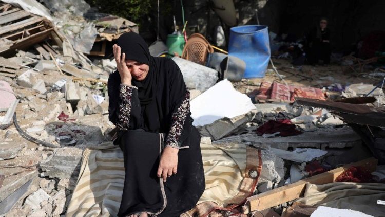 A woman sits amid the rubble of her house in Gaza