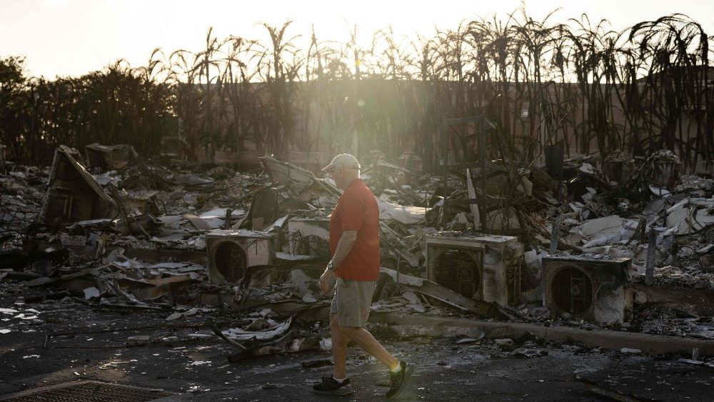 Um residente olha ao redor de um complexo de apartamentos carbonizado após um incêndio florestal em Lahaina, oeste de Maui, Havaí, em 12 de agosto de 2023.   (Foto de Yuki IWAMURA/AFP)