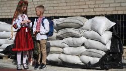 Estudantes ucranianos na frente de sacos de areia no pátio da escola após a cerimônia do Primeiro Sino, que marca o início do ano letivo na cidade de Lviv, no oeste da Ucrânia, em 1º de setembro de 2023. (Foto de YURIY DYACHYSHYN / AFP)