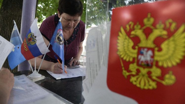 A woman receives her ballot papers at a polling station in Russian-occupied Donetsk