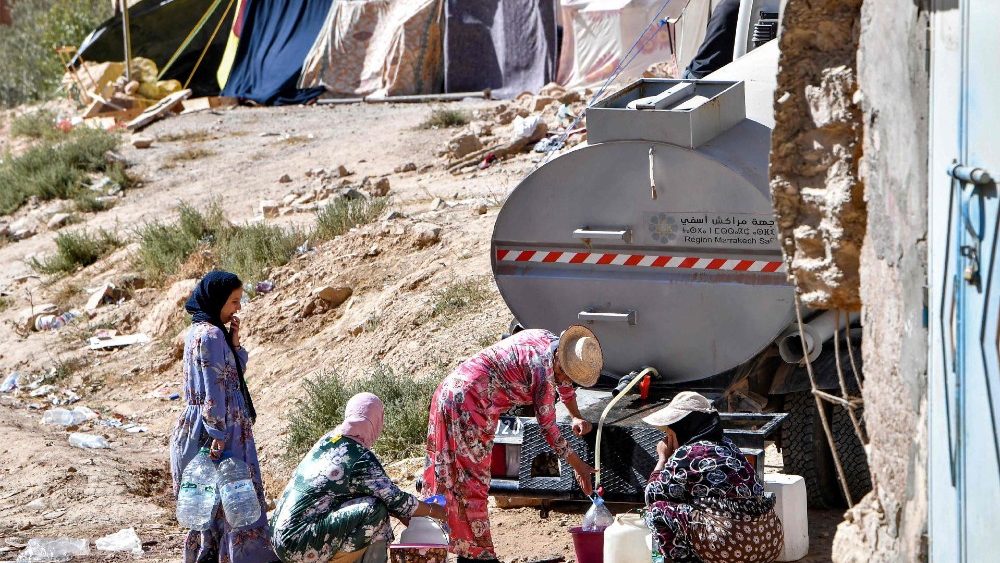 Sobreviventes se abastecem de água em um caminhão-tanque na vila de Ineghede, atingida pelo terremoto. (Photo by FETHI BELAID / AFP)