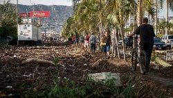 People walk amid debris left in the wake of Hurricane Otis