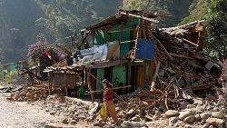 A survivor of an earthquake in Nepal walks past a ruined house