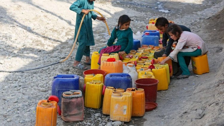Children collect drinking water along a roadside in Jalalabad, Afghanistan