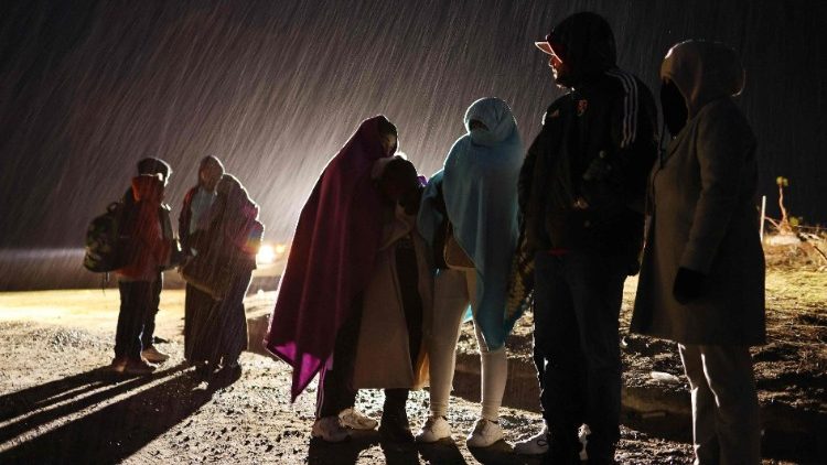 Asylum seeking migrants stand in the rain before being transported to a U.S. Border Patrol processing center