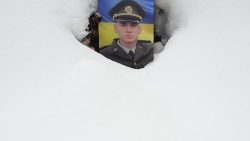 Retrato de um soldado ucraniano em seu túmulo, coberto de neve, durante o Dia das Forças Armadas da Ucrânia, no cemitério de Lychakiv, na cidade de Lviv. (Foto de YURIY DYACHYSHYN/AFP)
