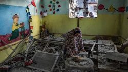 A woman tries to salvage some books inside a kindergarten hit by Israeli bombing in Rafah in the southern Gaza Strip on 9 December 2023