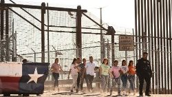 Migrants board vans after waiting along the US border wall