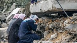 Palestinian women cry where a relative is believed to be trapped in debris following Israeli bombardment in Rafah in the southern Gaza Strip