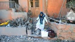 A woman walks through rubble outside a building following strikes on the the town of Naqura in southern Lebanon close to the border with northern Israel