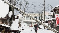 Japonesa caminha em estrada nevada em meio à destruição na cidade de Suzu, província de Ishikawa. (Photo by JIJI Press / AFP)