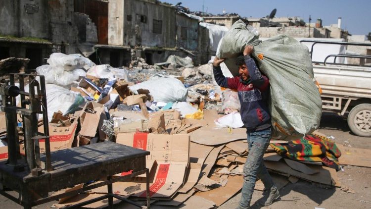 Saleh, a 13 year-old displaced Syrian boy, carries a bag of recyclable items in Idlib province