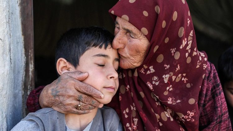 Eine ältere Frau hält einen erschöpften Jungen im Arm.