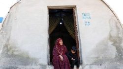 Eine Syrerin sitzt mit ihrem Enkel vor einer Notunterkunft an der türkischen Grenze