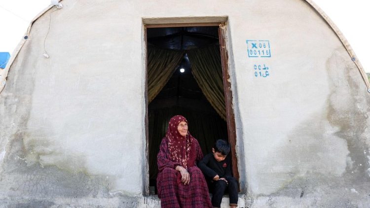 Eine Syrerin sitzt mit ihrem Enkel vor einer Notunterkunft an der türkischen Grenze