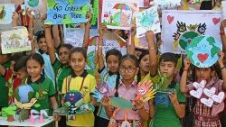 Ученици държат своите картини и модели с екологични теми по случай „Деня на Земята“ в училище в Амритсар