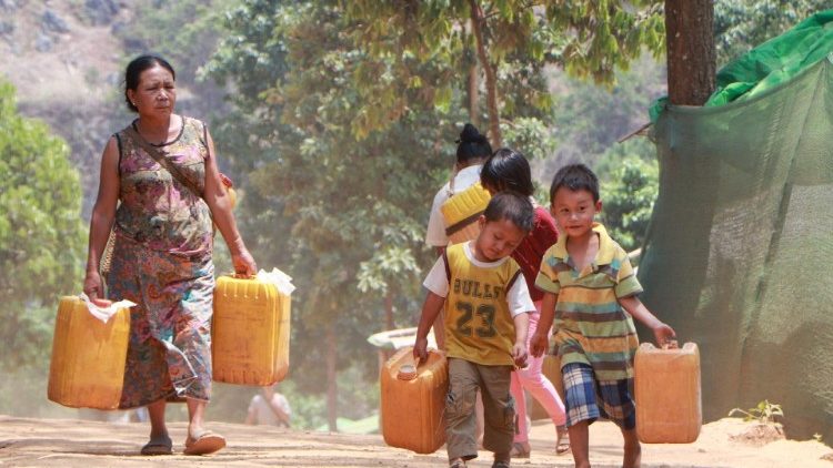 Mãe e filhos carregam água potável em campo de deslocados internos em Demoso, Mianmar.