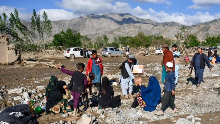 Afghans sit near damaged houses after floods in Burka district of Baghlan province 