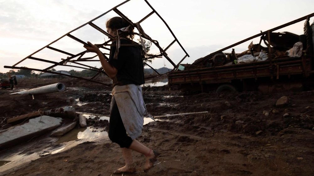 Uma mulher carregando destroços caminha descalça por uma rua do bairro Passo de Estrela, em Cruzeiro do Sul, Rio Grande do Sul, Brasil, em 5 de junho de 2024. (AFP/Silvio Avila)