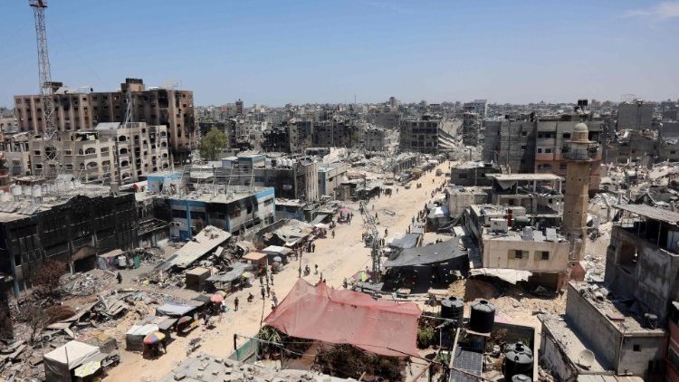 Vendors sell food and goods outside the burnt-out ruins of a UN agency in Jabalia