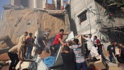 Alcuni palestinesi cercano sopravvissuti sotto le macerie al campo profughi di al-Bureij