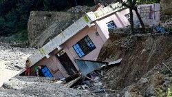 Women look at a damaged building uprooted after heavy rains near Kathmandu on October 1