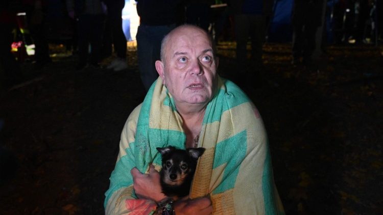 Um morador de um prédio de apartamentos danificado após um ataque aéreo segura seu cachorro nos braços após evacuar o prédio, em Kharkiv, em 31 de outubro de 2024, em meio à invasão russa na Ucrânia. (Foto de SERGEY BOBOK / AFP)