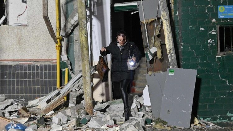 Uma moradora de um prédio de apartamentos danificado após um ataque aéreo caminha sobre escombros ao sair do prédio, em Kharkiv, em 31 de outubro de 2024, em meio à invasão russa da Ucrânia. (Foto de SERGEY BOBOK / AFP)