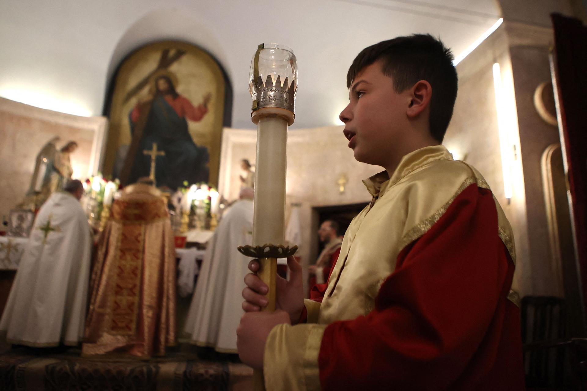 Um coroinha segura uma vela durante celebração na Igreja de Santa Bárbara, em Aleppo  (Foto de AAREF WATAD / AFP)