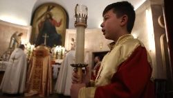 Um coroinha segura uma vela durante celebração na Igreja de Santa Bárbara, em Aleppo  (Foto de AAREF WATAD / AFP)