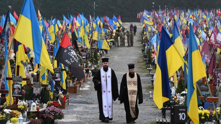 Sacerdotes visitam o cemitério de Lychakiv no Dia das Forças Armadas da Ucrânia, em Lviv, em 6 de dezembro de 2024, em meio à invasão russa da Ucrânia. (Foto de YURIY DYACHYSHYN / AFP)