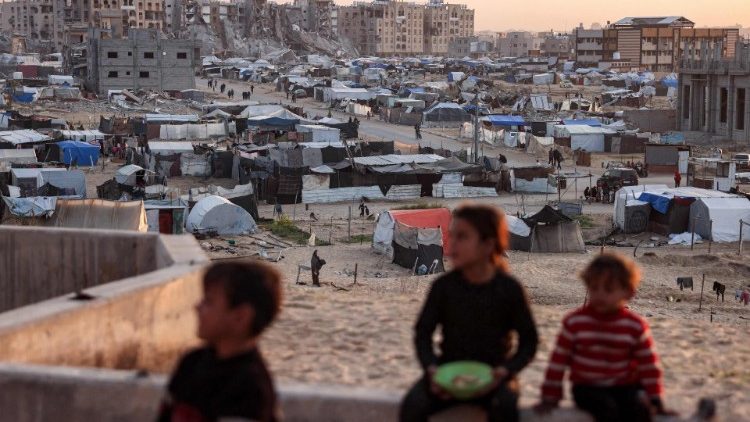 Children sit together at a refugee complex in Khan Yunis, in Gaza