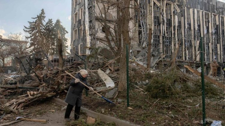 Uma mulher limpa escombros ao redor de um prédio fortemente danificado perto do local de um ataque de míssil em Izyum, região de Kharkiv, em 4 de fevereiro de 2025, em meio à invasão russa da Ucrânia. Um ataque de míssil russo em 4 de fevereiro de 2025 na cidade ucraniana de Izyum, brevemente ocupada pela Rússia em 2022, matou cinco pessoas e feriu mais três dúzias, disseram autoridades. (Foto de Roman PILIPEY / AFP)