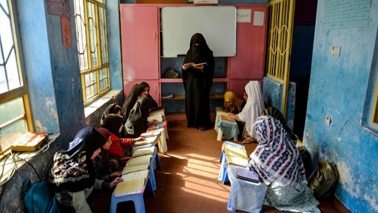 An Afghan woman teaches girls as they read a religious book at a madrassa or Islamic school in Kandahar