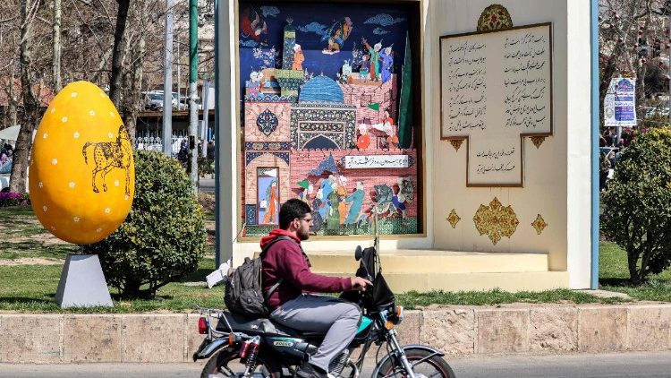 A man rides a motorcycle past an installation of an open book with poetry verses from the Divan of Hafez, by 14th-century Persian poet Hafez-e-Shirazi, in Iran
