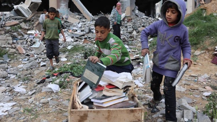 फिलिस्तीनी बच्चे  आग जलाने के लिए किताबों को एकत्रित करते हुए