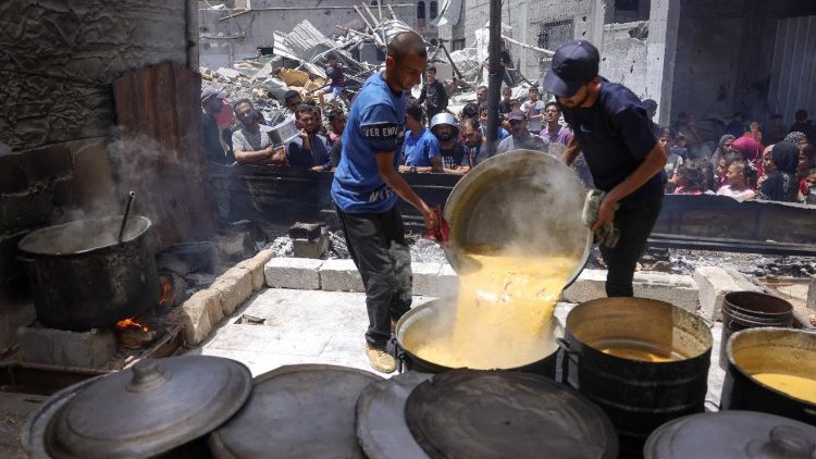Volunteers prepare cooked food to be distributed to displaced Palestinians at a charity distribution in Jabalia in the northern Gaza Strip