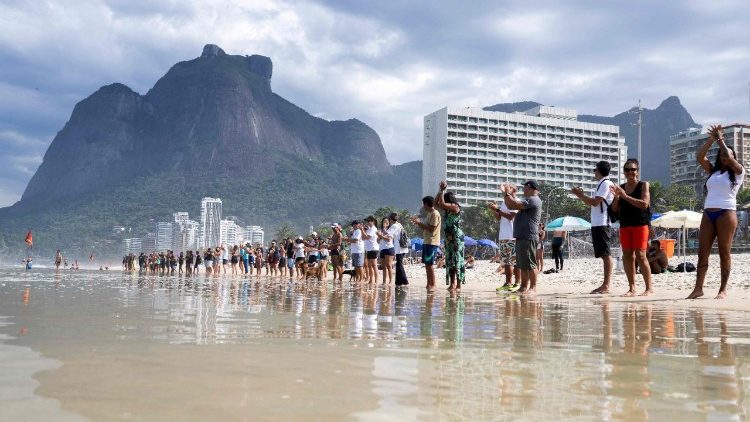 Des Brésiliens se tiennent symboliquement la main pour étreindre l'océan, à l'occasion de la Journée mondiale des océans, à Rio de Janeiro (Brésil), le 8 juin 2025.