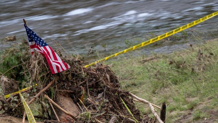 An American flag sits atop a pile of debris on the banks of the Guadalupe River in Kerrville, Texas